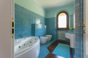 a blue tiled bathroom with a tub and two toilets at VILLA TERRABIANCA - Premium Villas in Tortoreto Lido +22 photos