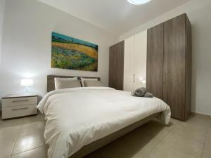 - une chambre avec un lit blanc et une peinture murale dans l'établissement Rock Bay, à Birżebbuġa