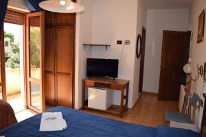 Habitación con cama y mesa con TV. en Hotel Garden en Nuraminis