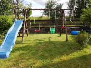 a playground with a slide and swings in a yard at FeWo Mädi in Windeck