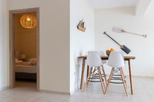 a dining room with a table and two white stools at Grand Bleu Apartments & Villas in Ermioni