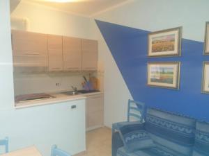 eine Küche mit einer blauen Wand mit einer Theke und Stühlen in der Unterkunft Casa Centurione Silvi Marina in Silvi Marina