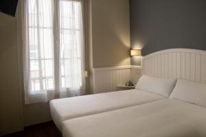 a bedroom with a white bed and a window at Alda Miramar Rooms in Gijón