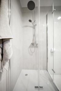 y baño con ducha y puerta de cristal. en Niron Apartament Dom z Papieru Sztokholm, en Piła