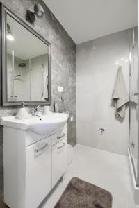 y baño blanco con lavabo y ducha. en Niron Apartament Dom z Papieru Sztokholm en Piła