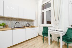 a kitchen with white cabinets and a white table and chairs at Niron Apartament Dom z Papieru Sztokholm in Piła