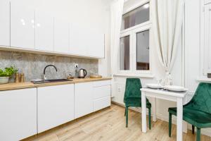 kuchnia z białymi szafkami oraz białym stołem i krzesłami w obiekcie Niron Apartament Dom z Papieru Sztokholm w mieście Piła +5 zdjęć