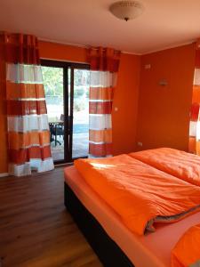 a bedroom with a bed with an orange comforter at Ferienwohnungen am Moselbeach in Mehring