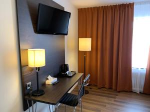a hotel room with a desk with a television on the wall at Slagsta Motell & Wärdshus in Norsborg