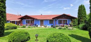 a blue house with a green yard at Magyar Apartmanházak I-III. in Zalakaros