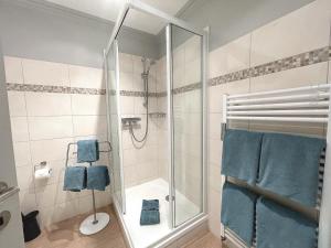 La salle de bains est pourvue d'une douche et de serviettes bleues. dans l'établissement Haus Stübbe beim Dorfteich, à Wenningstedt