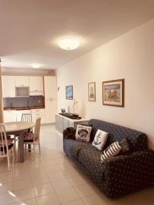 a living room with a couch and a table and a kitchen at Punta Ala Flat in Punta Ala