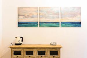 four paintings of the ocean on a wall at G25 Guesthouse in Monopoli