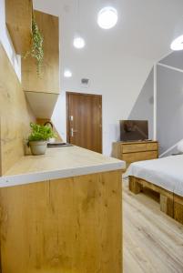 a kitchen with wooden cabinets and a bed in a room at Niron Apartament Dom z Papieru Tokio in Piła