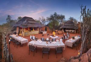 einen Essbereich im Freien mit Tischen, Stühlen und einem Grill in der Unterkunft Madikwe Hills Private Game Lodge in Madikwe Game Reserve