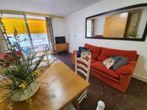 uma sala de estar com um sofá vermelho e uma mesa em Apartamento America em Lloret de Mar
