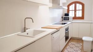 - une cuisine blanche avec évier et four micro-ondes dans l'établissement Casa Naiman - Roda de Bara, à Roda de Bará