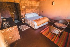 1 dormitorio con 1 cama, mesa y sillas en Eco-Lodge El Andinista en San Pedro de Atacama