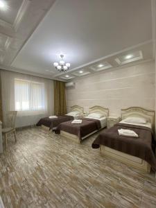 Habitación con 3 camas y lámpara de araña. en Mini Hotel Business class, en Krivoy Rog
