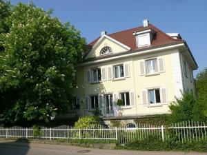 una gran casa blanca con una valla delante en Ferienwohnung Lavendel, en Sinzheim