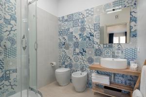 un bagno con piastrelle bianche e blu sul muro di Scrusciu du mari a San Vito lo Capo
