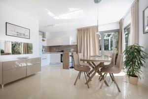 a white kitchen with a glass table and chairs at Villa del Mar in Mali Lošinj