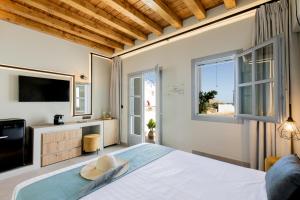 a bedroom with a bed and a tv and windows at Lindos Serenity Suites in Líndos