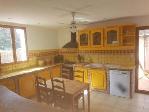 uma cozinha com armários amarelos, uma mesa e cadeiras em Maison à la semaine em Vitrolles