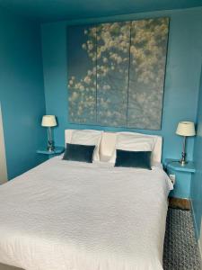 a blue bedroom with a large white bed with two lamps at Duplex LE GLENCOE in Honfleur