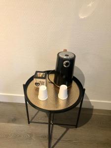 a table with a coffee maker and two cups on it at Hôtel Le 23 in Clichy