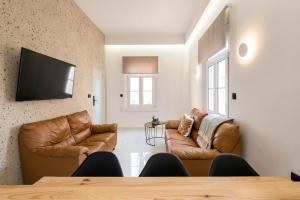 a living room with two leather chairs and a flat screen tv at Alia Apartments in Rhodes Town