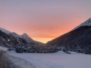 śnieżna droga w górach o zachodzie słońca w obiekcie Arlalps Apart w mieście Pettneu am Arlberg
