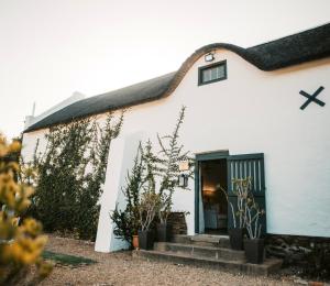 a white house with a black door and some plants at Jan Harmsgat Country House in Swellendam