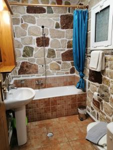 a stone walled bathroom with a tub and a sink at Athina EcoFarm in Ancient Epidauros