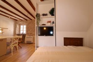a room with a bed and a refrigerator with a table at Old Šibenik Cozy Design Apartment in Šibenik