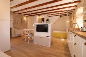 Una cocina y un comedor con televisión y una mesa. en Old Šibenik Cozy Design Apartment, en Šibenik