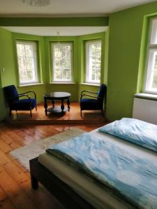 a green room with a bed and a table and chairs at Baltic Home in Polanica-Zdrój