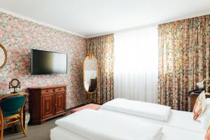 a hotel room with two beds and a tv on the wall at Das Kleine Hotel in ruhiger Stadtlage in Wiesbaden