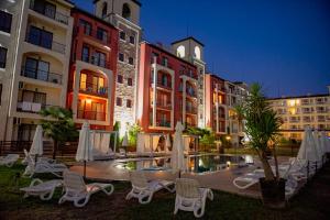 un patio del hotel con sillas, piscina y edificios en Menada Rocamar Apartments, en Tsarevo