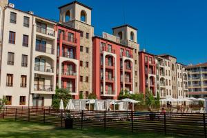 a group of buildings with tables and umbrellas in front at Menada Rocamar Apartments in Tsarevo