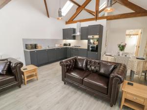 a living room with two leather couches and a kitchen at 1 Mountain View in Llangefni