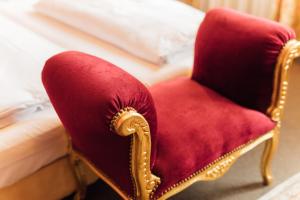 a red chair sitting next to a bed at Das Kleine Hotel in ruhiger Stadtlage in Wiesbaden