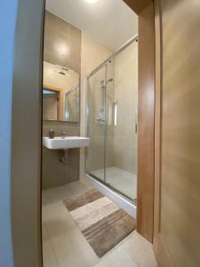 een badkamer met een glazen douche en een wastafel bij Hepburn Holiday Apartment in Birżebbuġa