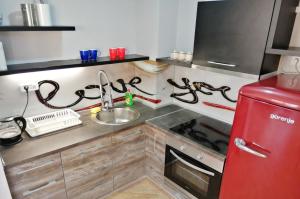 eine Küche mit einer Spüle und einem roten Kühlschrank in der Unterkunft Orange Lux Apartments in Budva