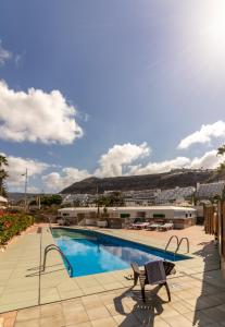 a swimming pool with two chairs and a building at Leticia del Mar Adults Only in Puerto Rico de Gran Canaria