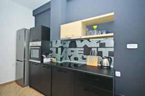 eine Küche mit einer schwarzen Theke und einem Kühlschrank in der Unterkunft Orange Lux Apartments in Budva