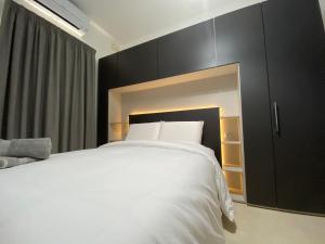 a bedroom with a white bed and a black cabinet at Hepburn Holiday Apartment in Birżebbuġa