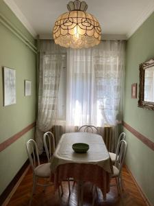 een eetkamer met een tafel met stoelen en een kroonluchter bij Hajnalka Apartmanház in Gyula