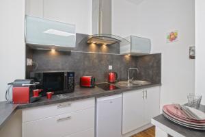 a kitchen with white cabinets and red appliances at Hyper Centre Rue Valdemaine in Angers