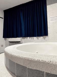 a bath tub in a bathroom with a blue curtain at Hotel Renovación in Caracas